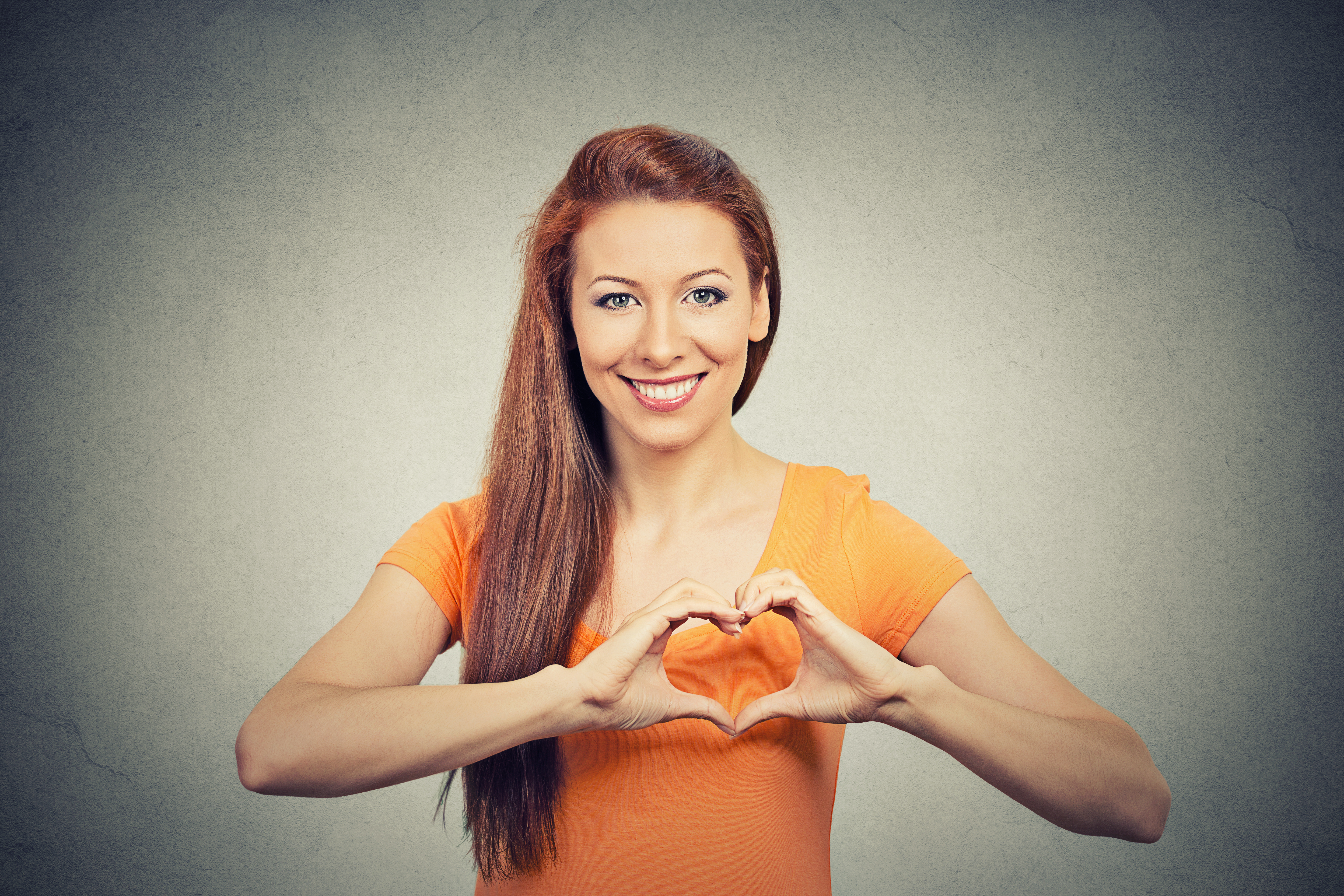 Closeup portrait smiling cheerful happy young woman making heart sign 