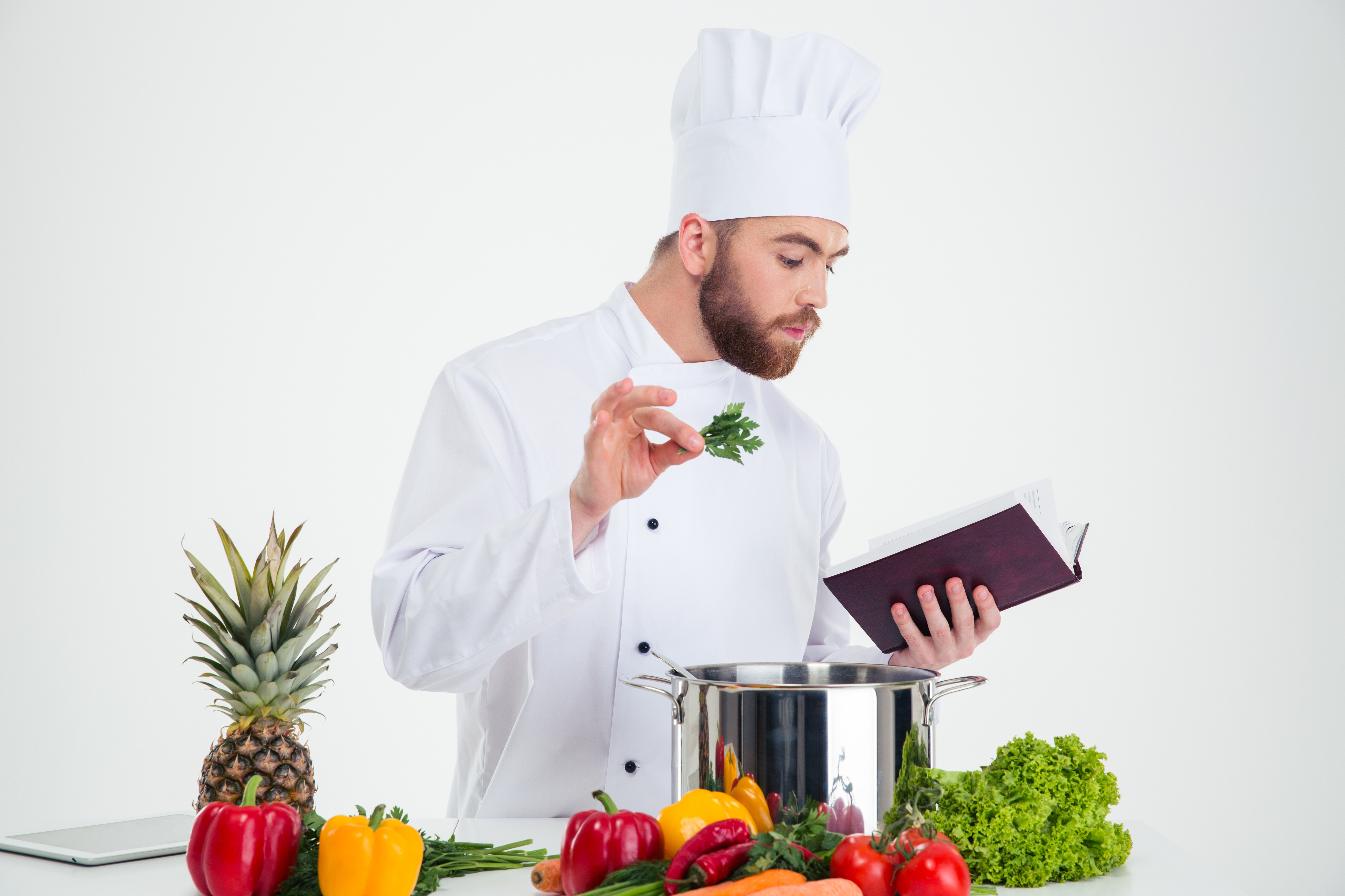 Portrait of a handsome male chef cook reading recipe book while prepar